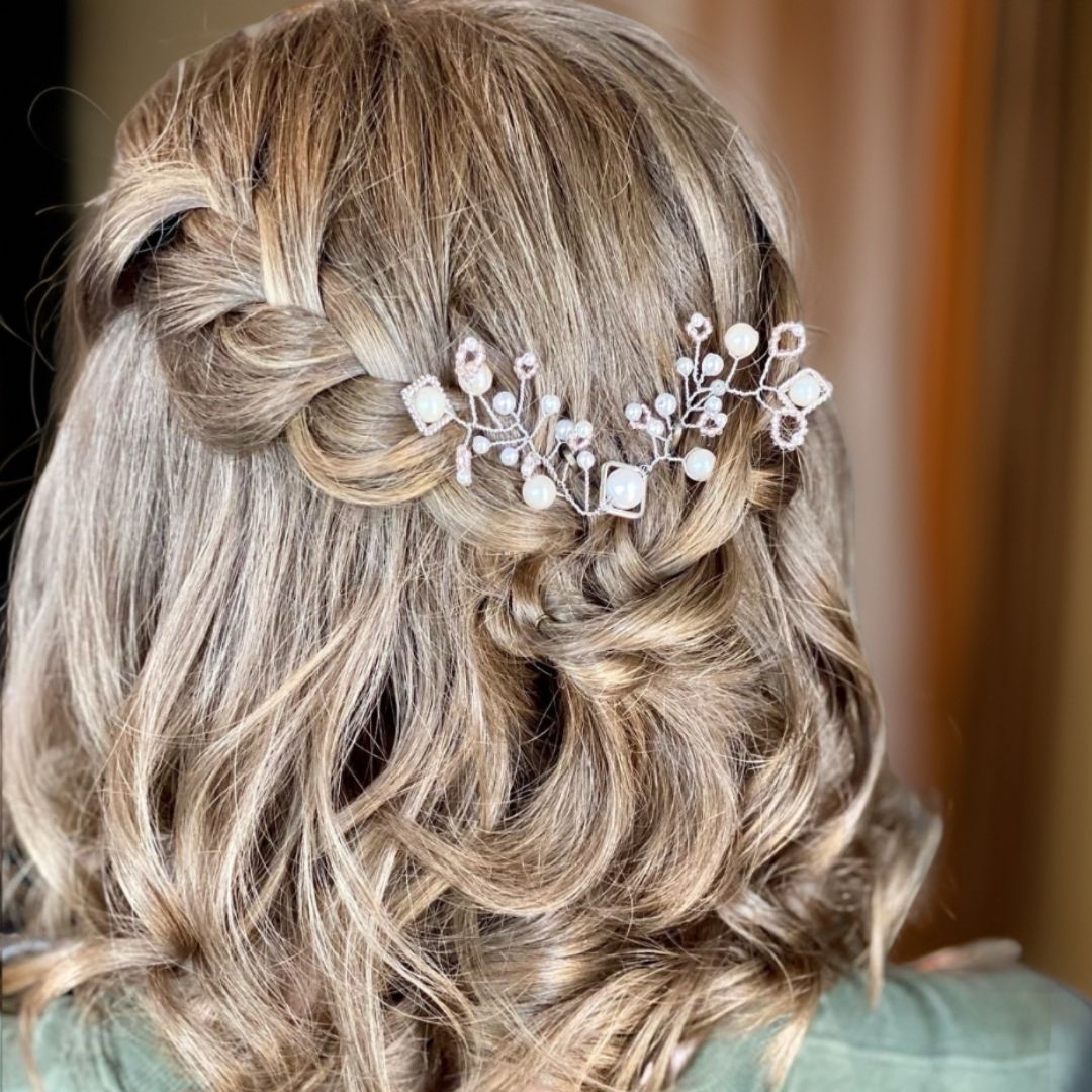 Bridal hair vine with white, cream, and pale pink pearls styled in soft curled updo hairstyle