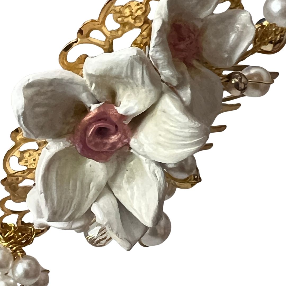 Close up of candlelight white bridal hair comb with hand-sculpted clay flowers, ivory pearls, and gold vine detail
