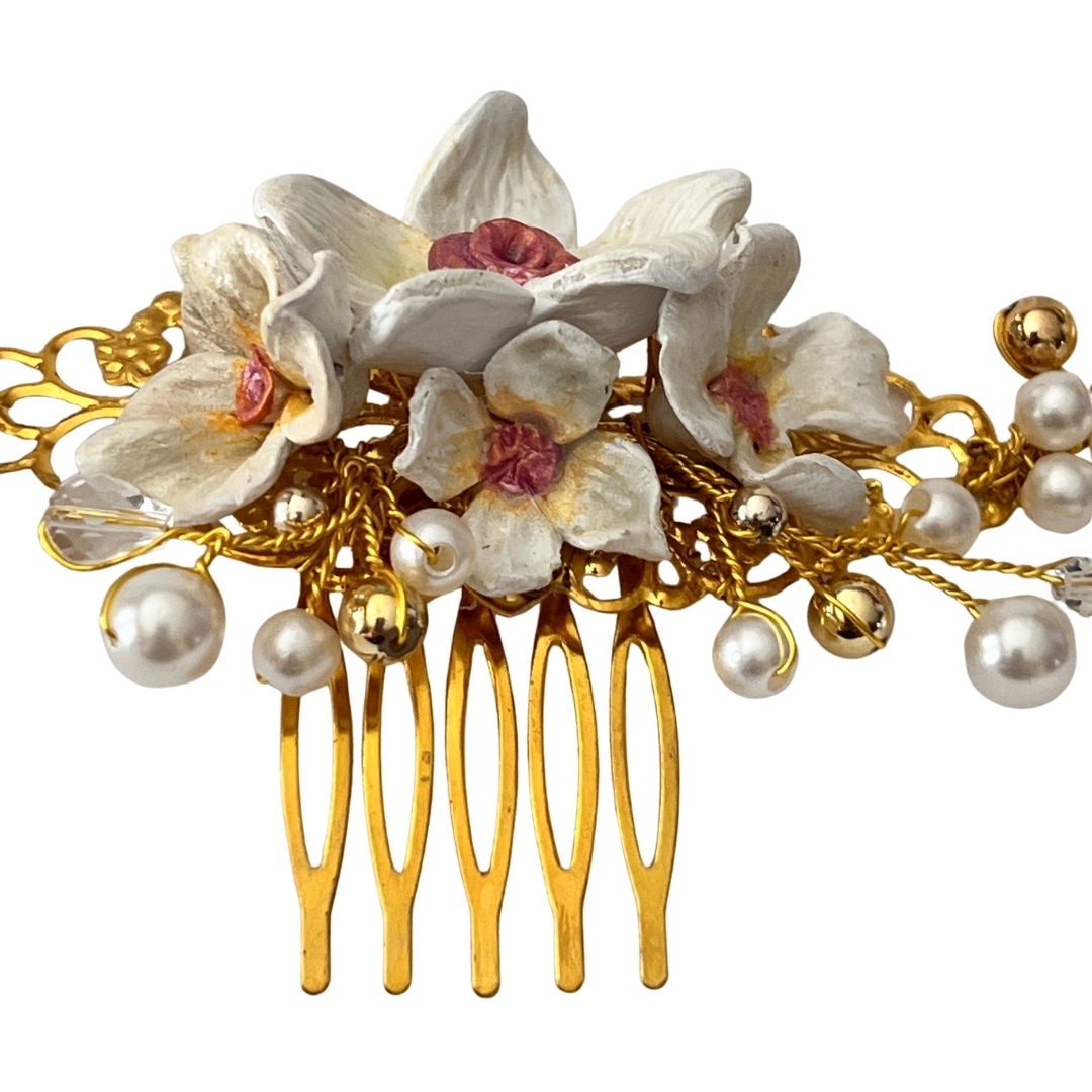 Candlelight white bridal hair comb with hand-sculpted clay flowers, ivory pearls, faceted crystals, and gold vine structure on comb base
