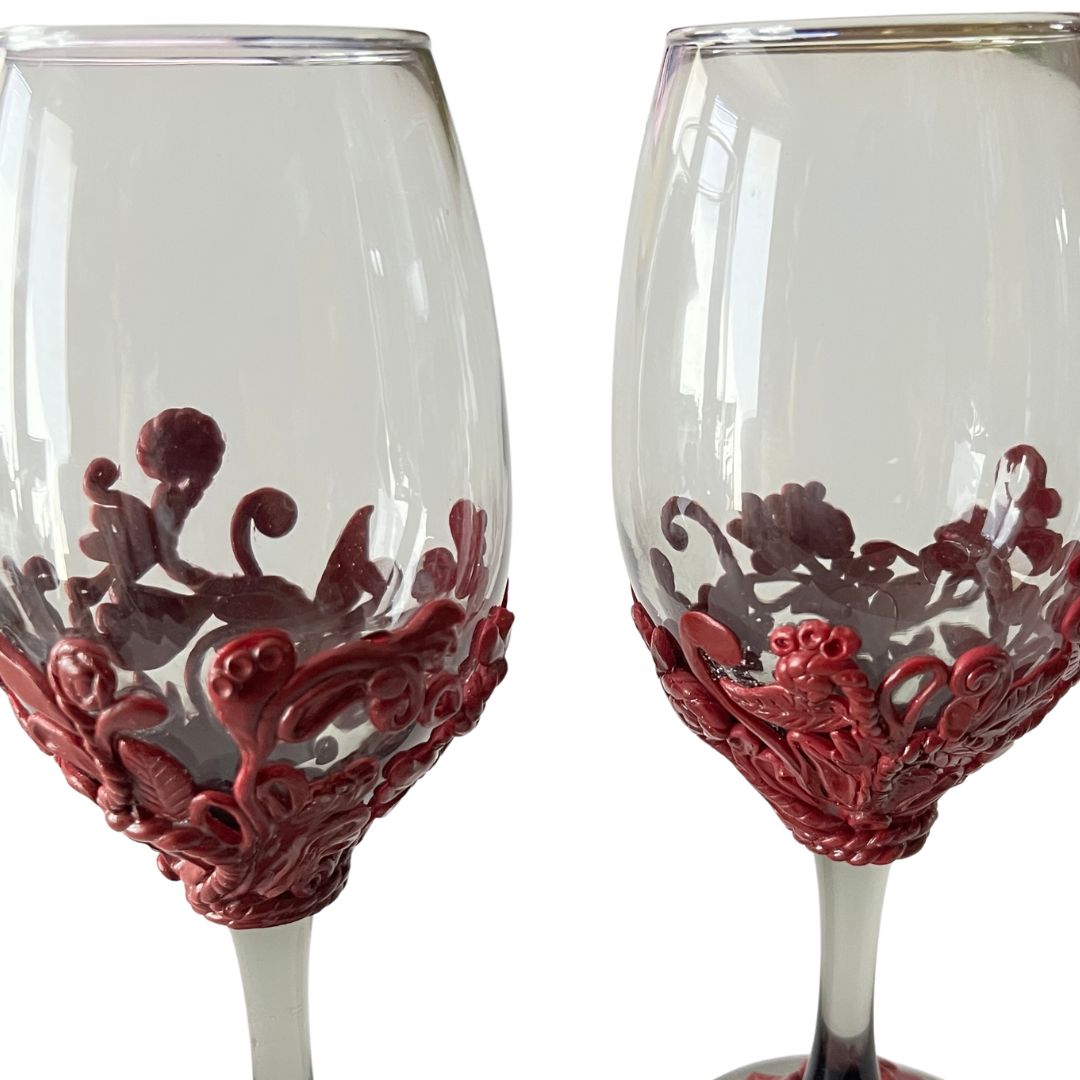 Close-up detail of hand sculpted burgundy scrollwork on smoky black wine glasses