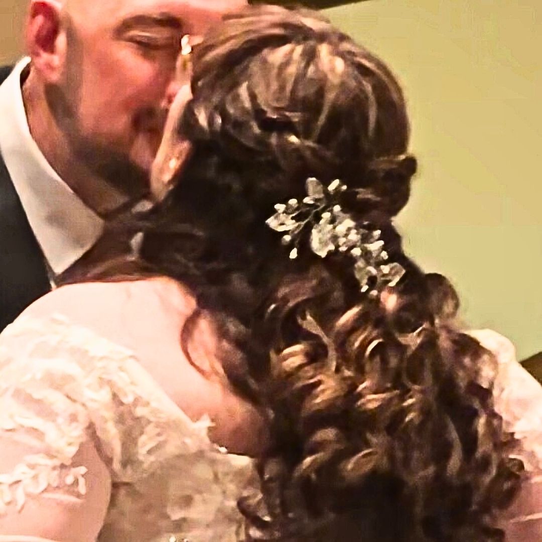 Bride wearing blush and white pearl bridal hair vine with crystal accents in curled wedding hairstyle