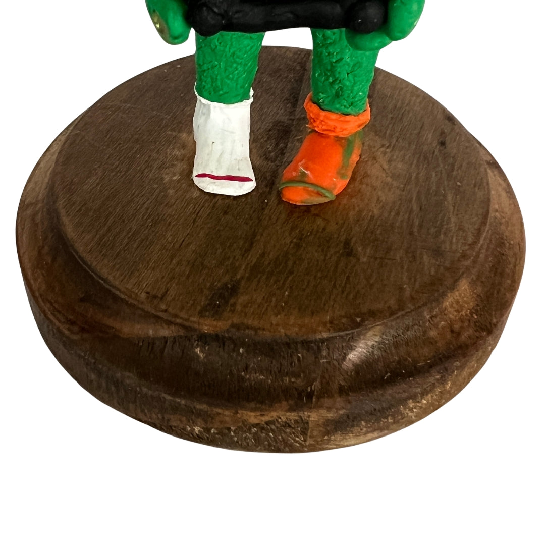 Green Game On gamer creature sculpture with purple hair and a controller on a walnut-stained wooden base.