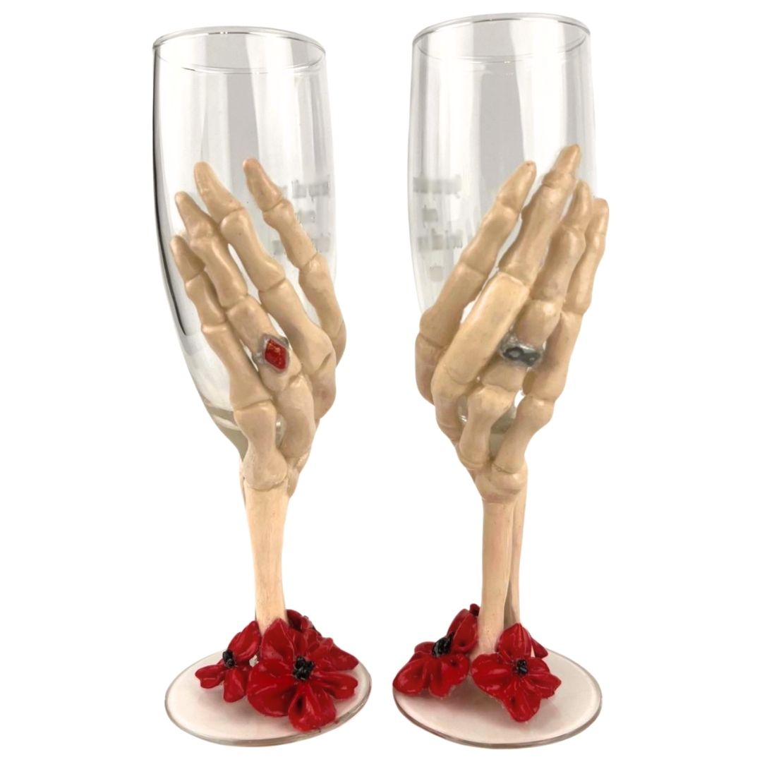 Hand sculpted skeleton hand champagne glasses with red floral base shown with black and red gothic wedding bouquet