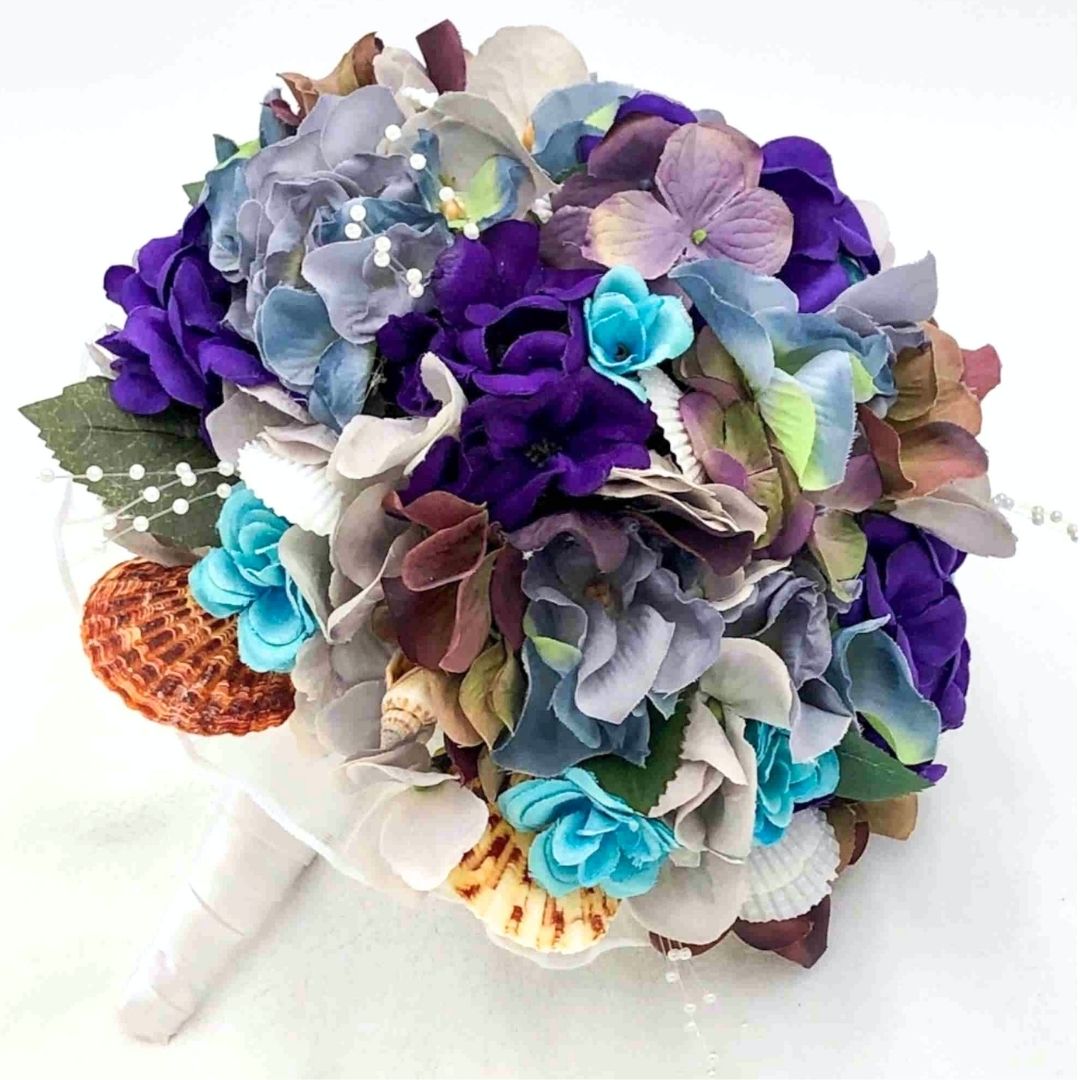 Purple and turquoise seashell bridesmaid bouquet with coastal flowers for beach weddings, handcrafted by Daree’s Designs
