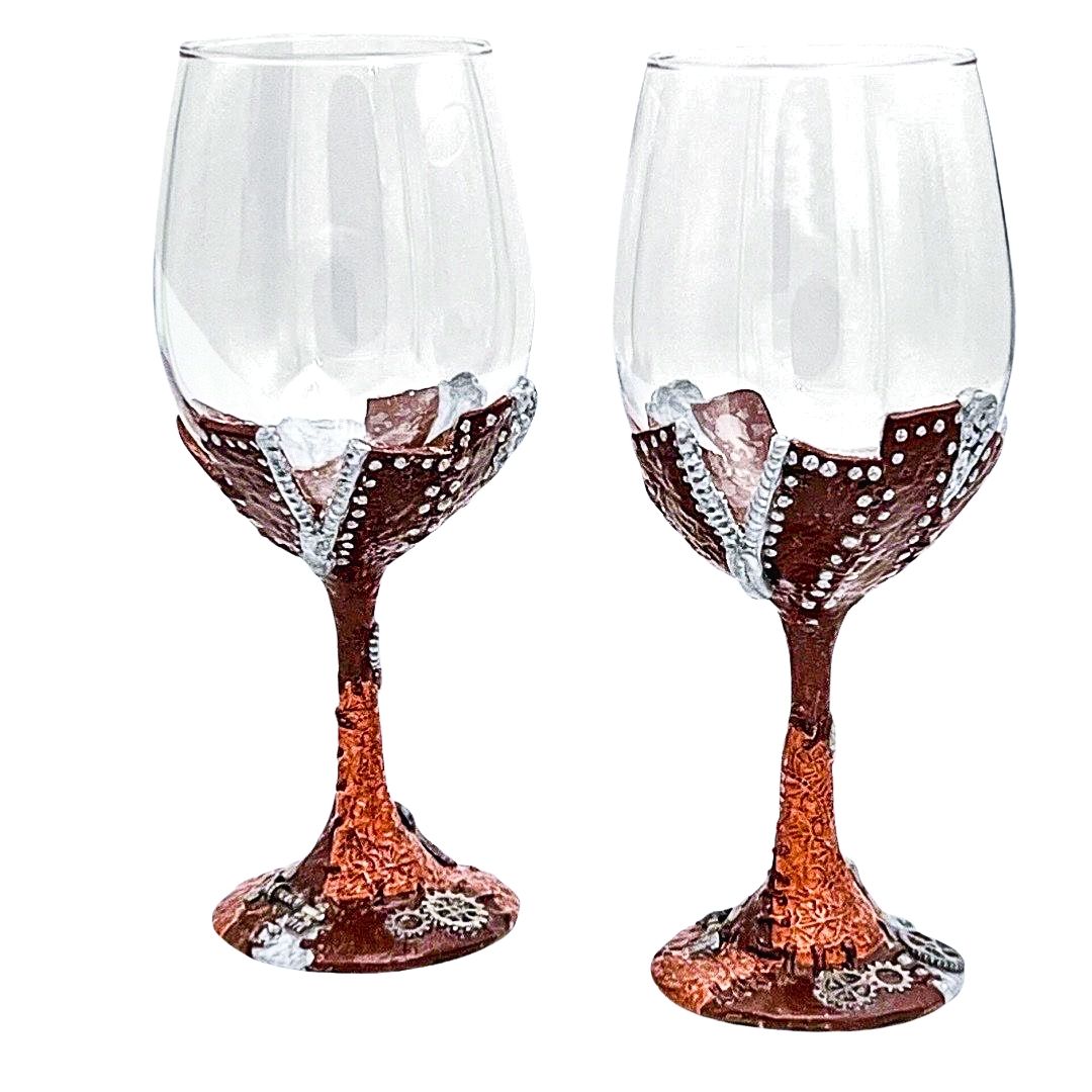 Hand sculpted steampunk wine glasses with copper polymer clay, silver stitching details, and gear embellishments on the base, handmade by Daree’s Designs