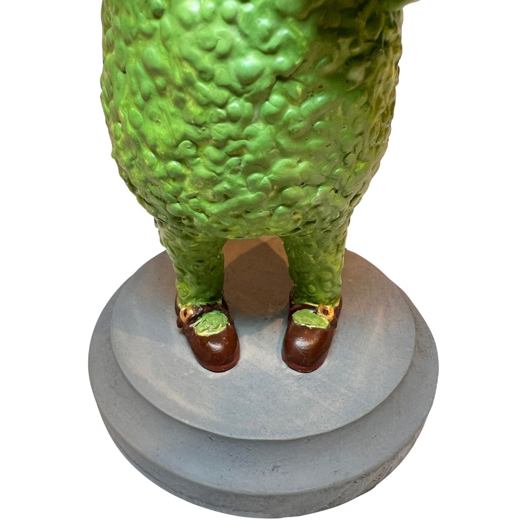 Detail of Tea & Biscuits’ textured green legs, brown shoes and weathered-gray wooden display base.