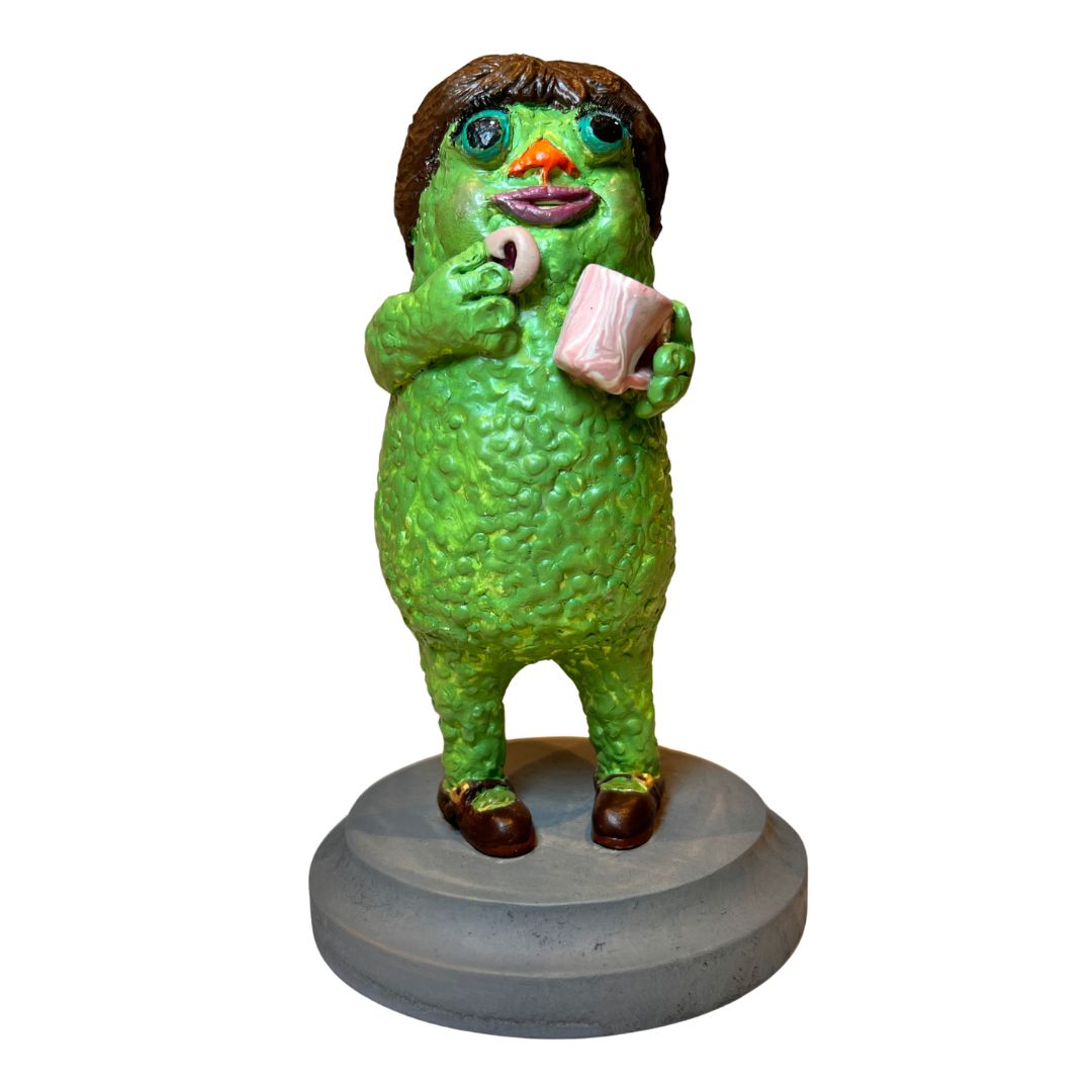 Green Tea & Biscuits creature sculpture holding a pink teacup and biscuit on a weathered-gray wooden base.