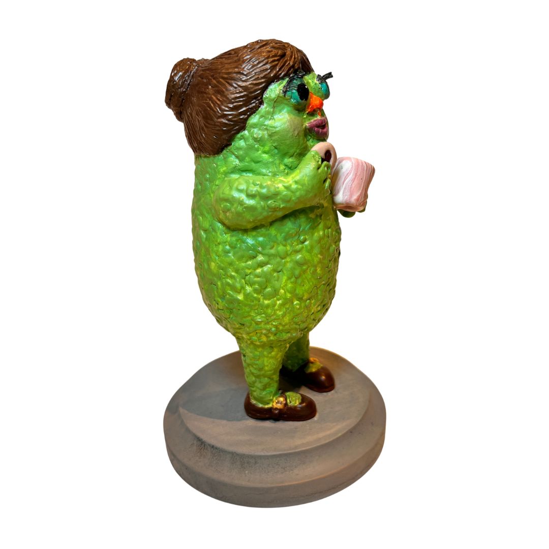Left-side view of Tea & Biscuits showing textured green skin, sculpted brown hair, teacup and biscuit.