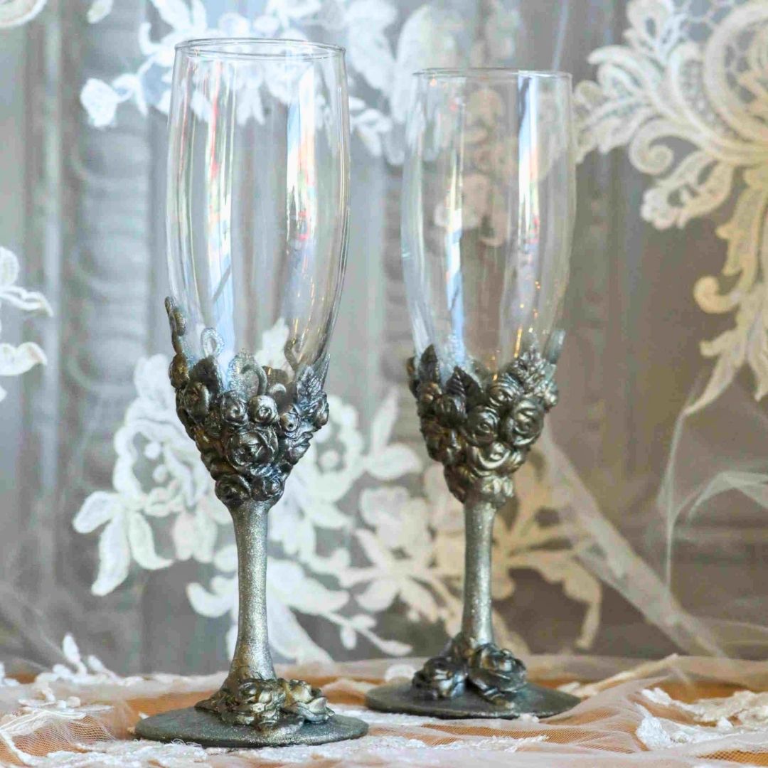 Victorian inspired silver champagne flute set displayed against lace backdrop with sculpted metallic roses