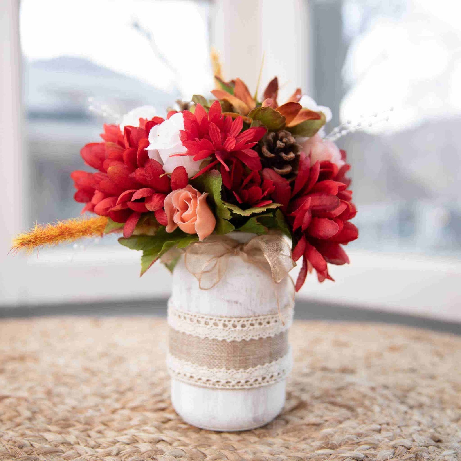 Add the feeling of Autumn to your celebration with our Autumn Mason Jar Centerpiece. This rustic mason jar centerpiece is the perfect compliment to an Autumn wedding. Adorned with burlap and lace, the mason jar holds seasonal silk flowers.