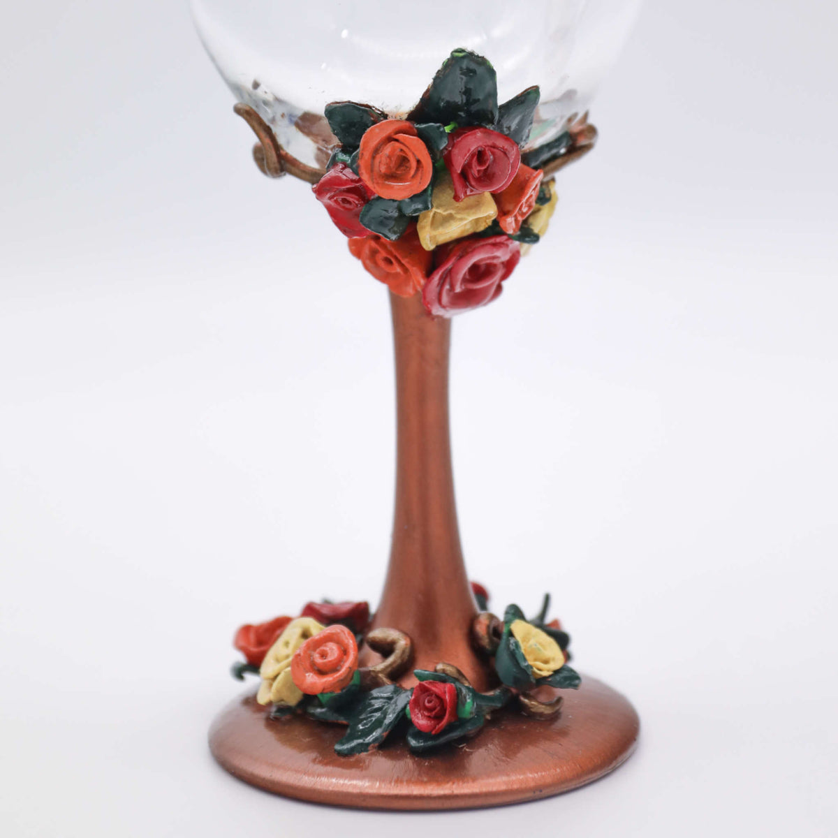 Each wine glass sits atop of rich metallic copper stem and is adorned with polymer clay flowers in red, orange, and yellow flowers within green leaves and vines.