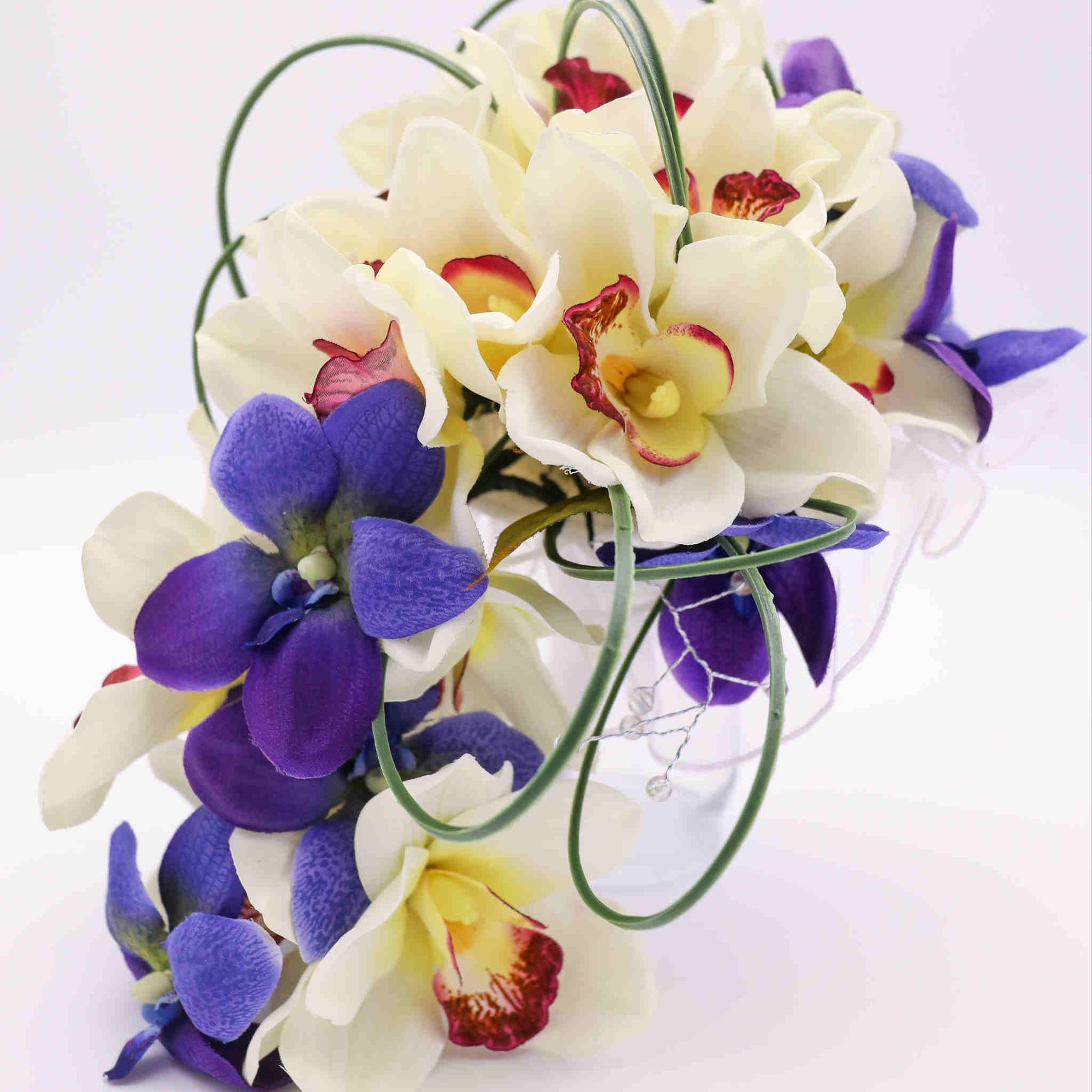 Created with silk orchids and various accent tropical flowers, greenery and clear sparkle stems, the bouquet sits atop a handle wrapped in satin to be both beautiful and comfortable.