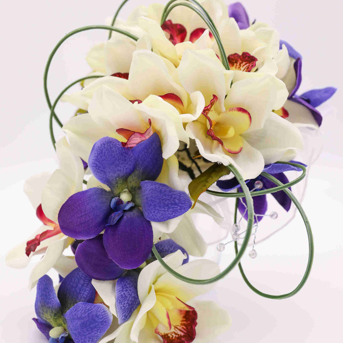 Created with silk orchids and various accent tropical flowers, greenery and clear sparkle stems, the bouquet sits atop a handle wrapped in satin to be both beautiful and comfortable.