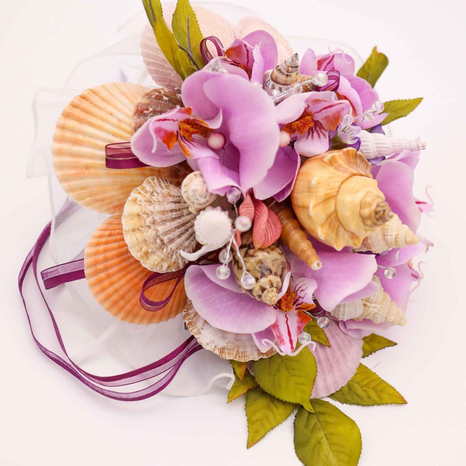 Bring the beauty of the beach to your tropical wedding ceremony. This cascading bouquet is adorned with various shells, silk orchids, ribbon, greenery and crystal bead stems.
