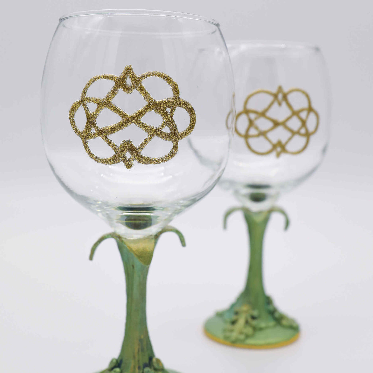 Perfect for any celebration. Each wine glass is adorned with the traditional love knot and sits atop a hand-scuplted polymer clay painted stem of green metallic leaves and vines.
