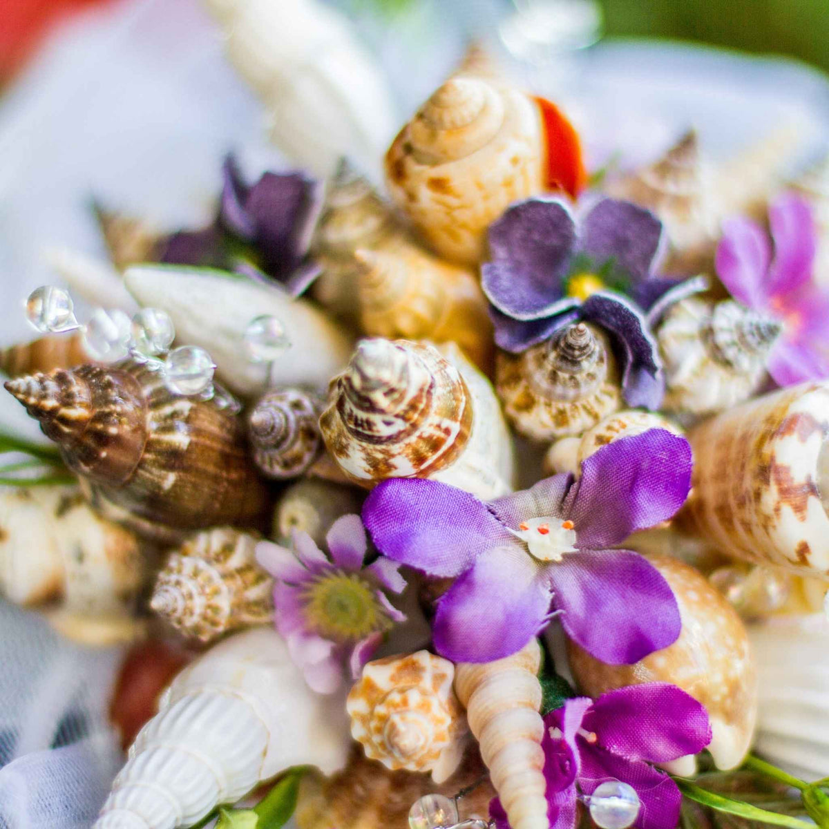 Bring the beach to your summer or tropical wedding ceremony set in greenery and adorned with cone shells and small silk flowers.
