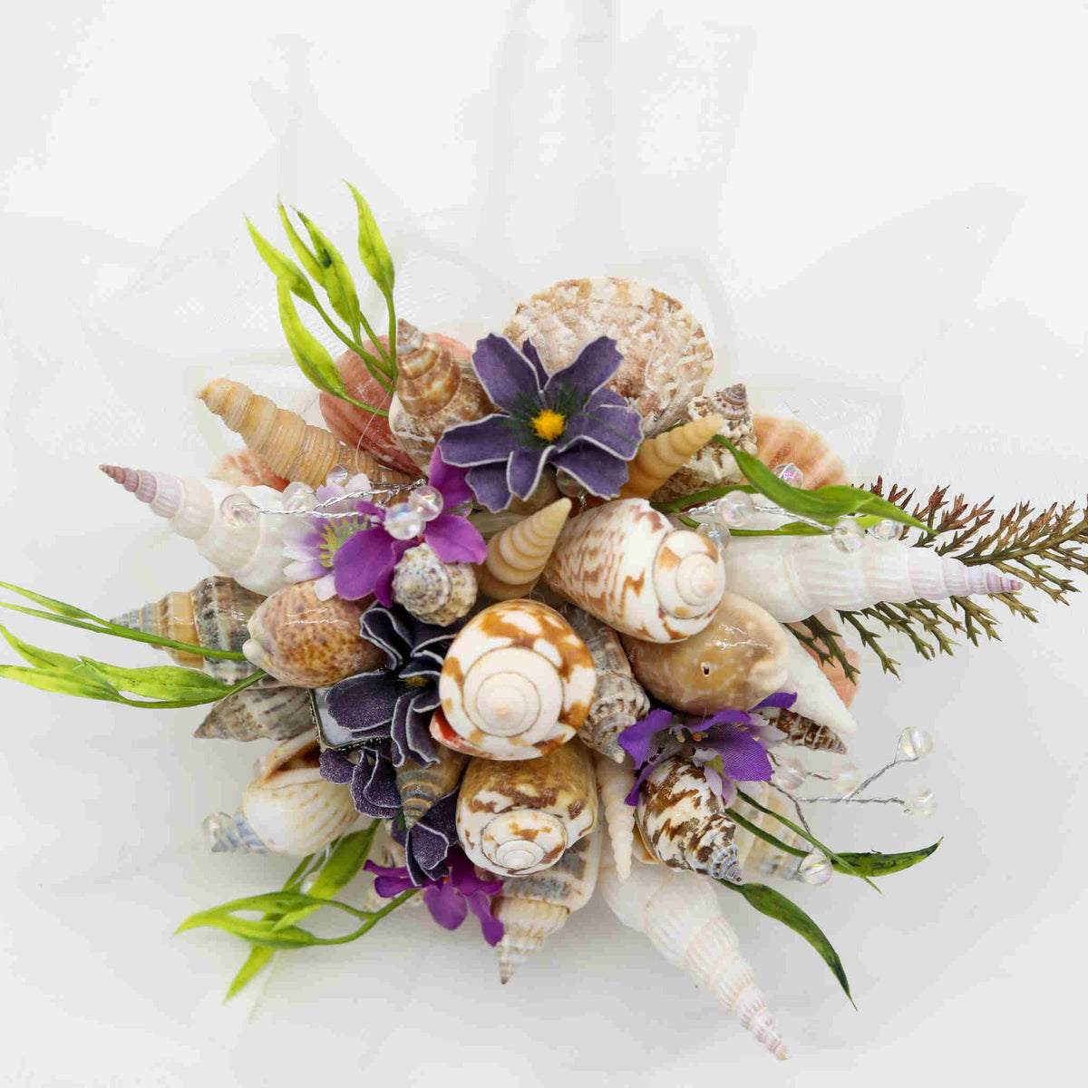 Bring the beach to your summer or tropical wedding ceremony set in greenery and adorned with cone shells and small silk flowers.