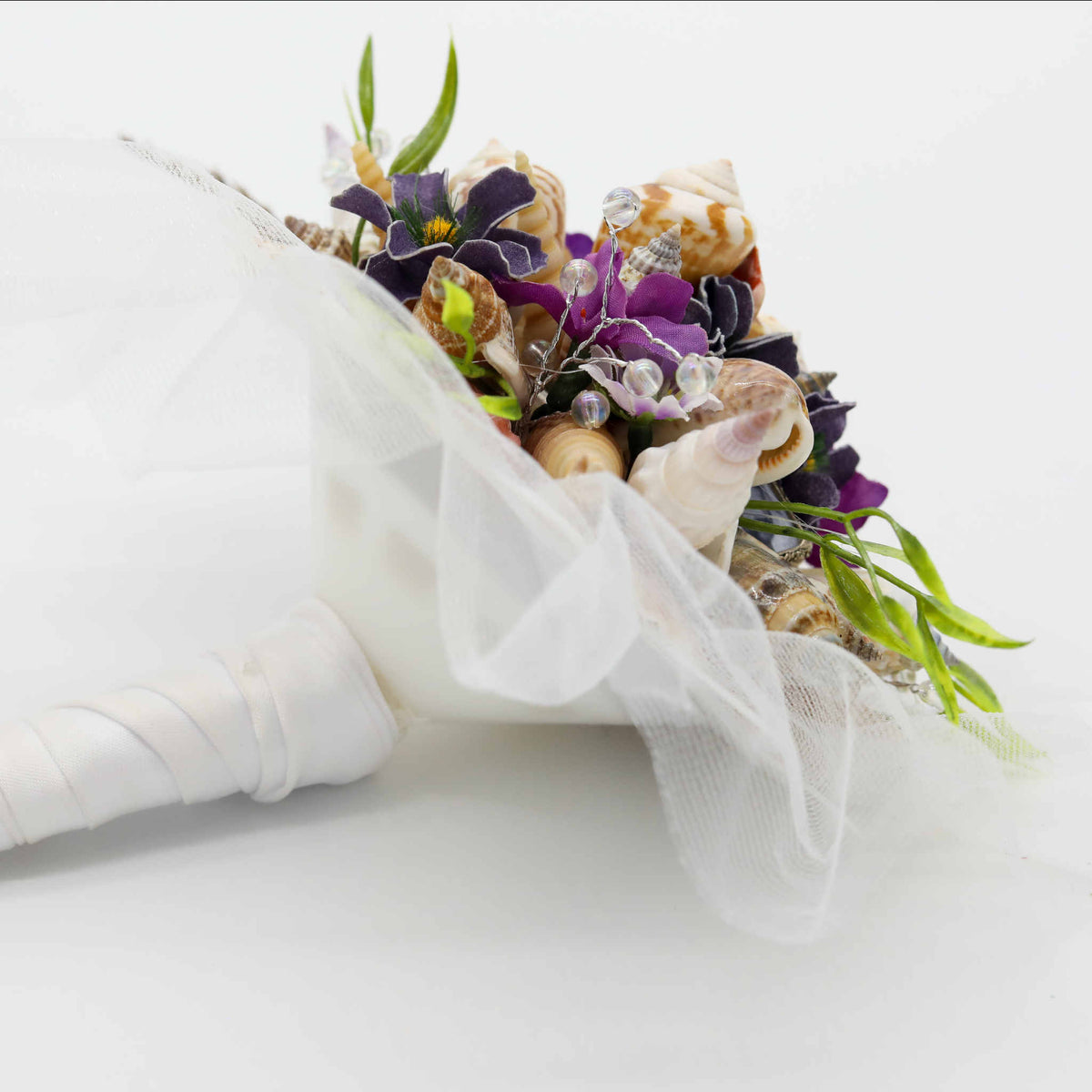 Bring the beach to your summer or tropical wedding ceremony set in greenery and adorned with cone shells and small silk flowers.