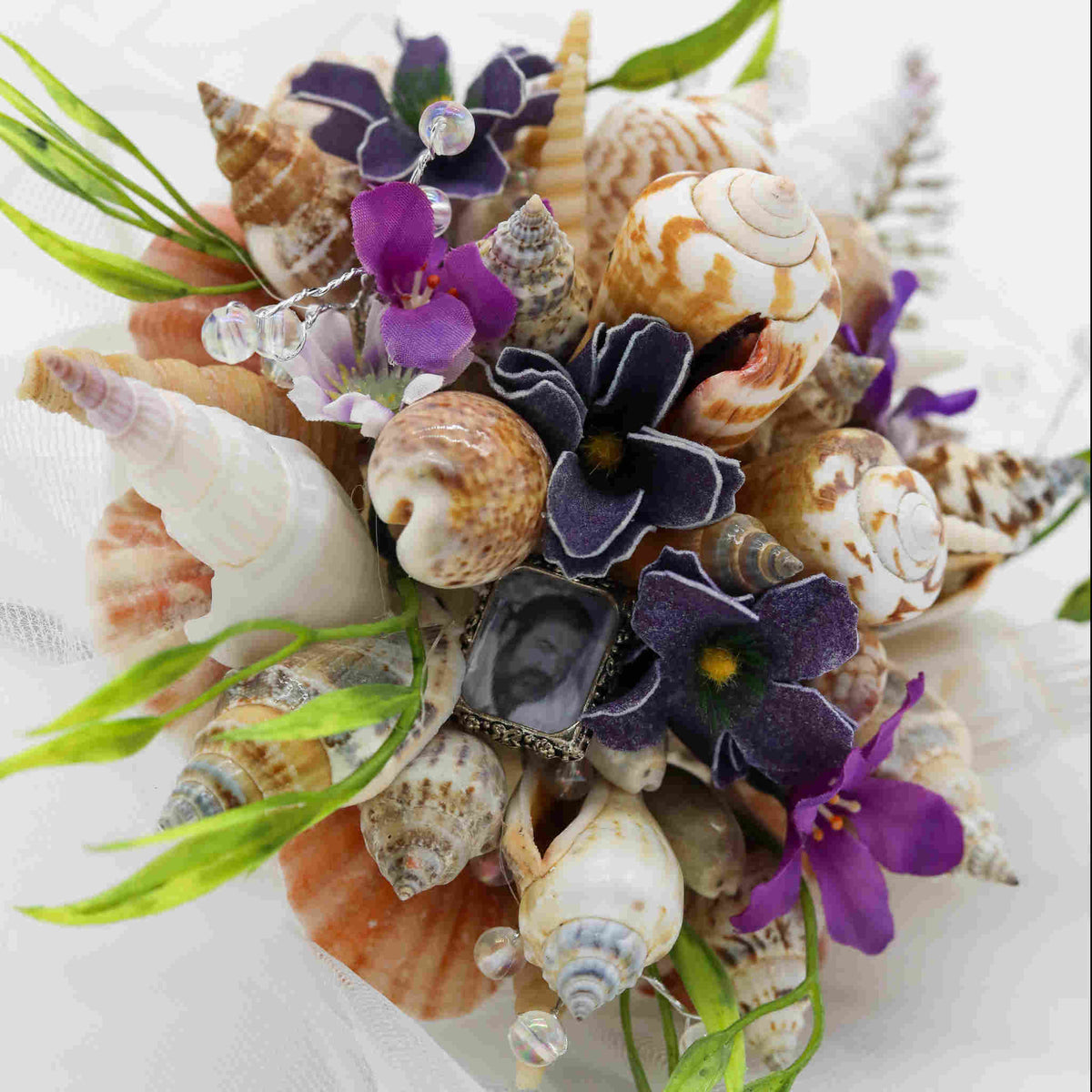 Bring the beach to your summer or tropical wedding ceremony set in greenery and adorned with cone shells and small silk flowers.