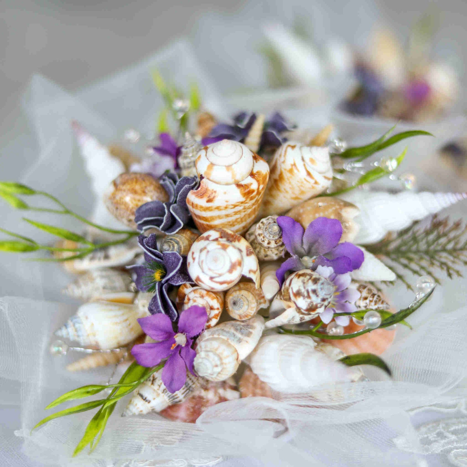 Bring the beach to your summer or tropical wedding ceremony set in greenery and adorned with cone shells and small silk flowers.