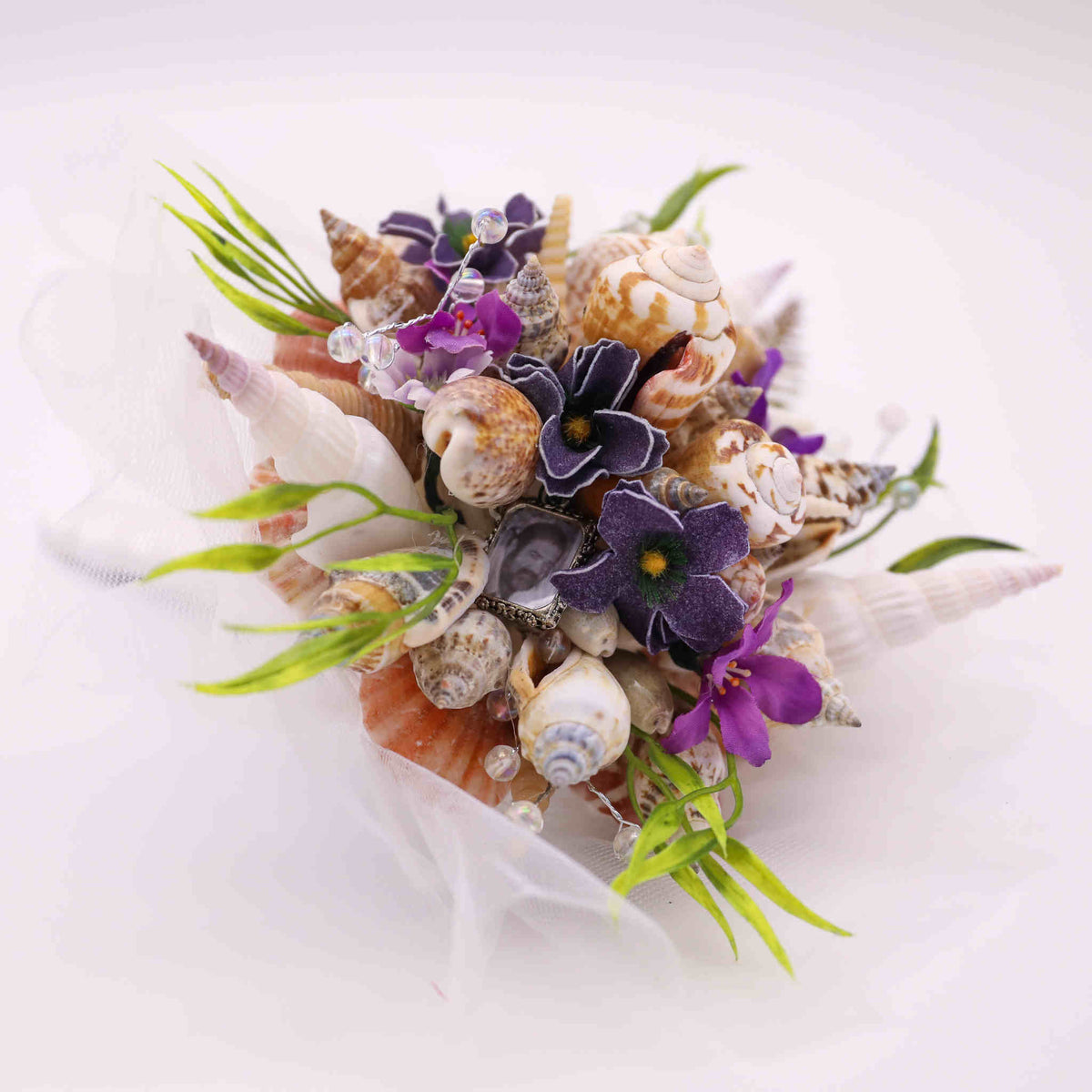 Bring the beach to your summer or tropical wedding ceremony set in greenery and adorned with cone shells and small silk flowers.