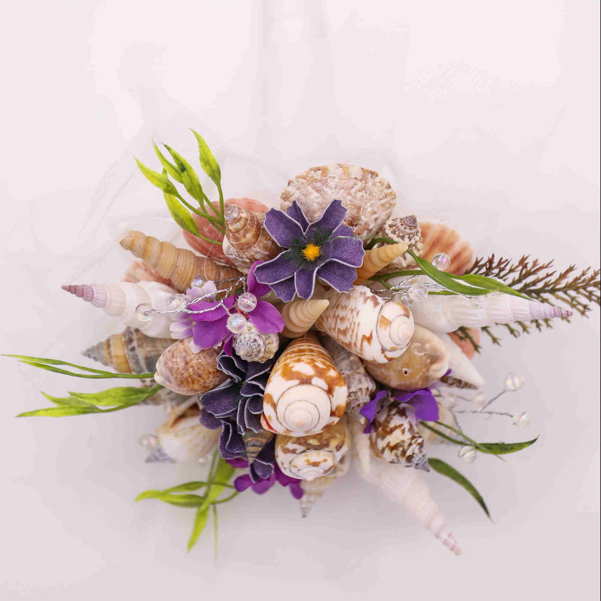 Bring the beach to your summer or tropical wedding ceremony set in greenery and adorned with cone shells and small silk flowers.